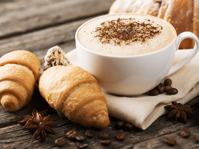 Чашка капучино на столе круассанами