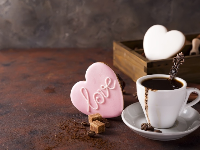 Чашка кофе на столе с сахаром и печеньем в форме сердца 