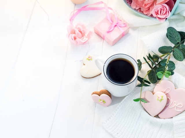 Чашка кофе на столе с печеньем в форме сердца и подарком