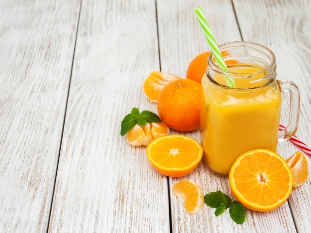 Свежий сок в стеклянной банке на столе с апельсинами