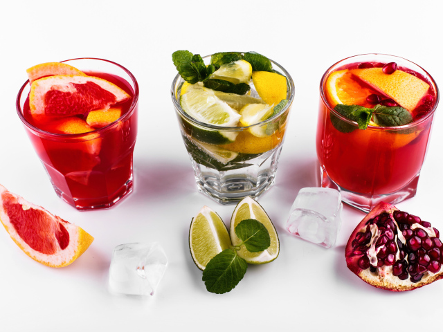 Стаканы с цитрусовыми коктейлями со льдом на белом фоне с фруктами