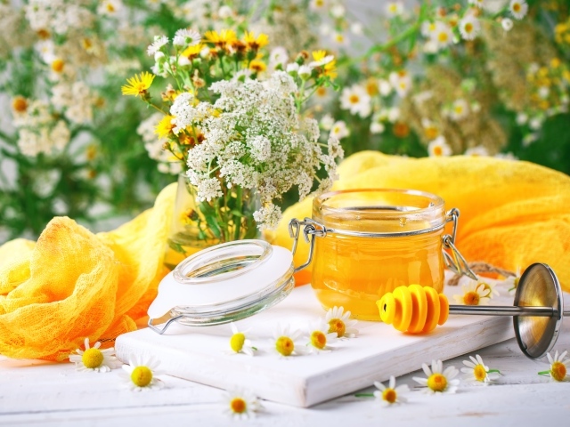 Банка меда на столе с цветами