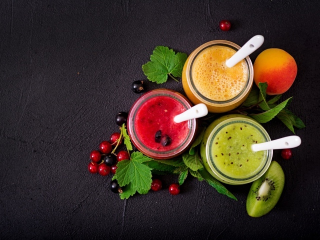Баночки со смузи на сером фоне с ягодами черной и красной смородины и киви
