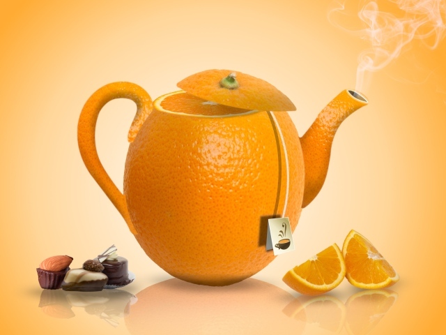 Чайник апельсин на оранжевом фоне с конфетами