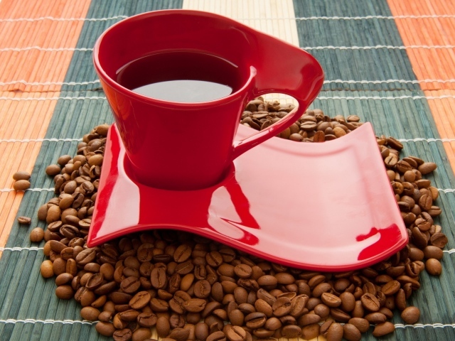 Красная чашка стоит на кофейных зернах 