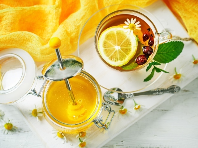 Чай с лимоном и шиповником на столе с медом