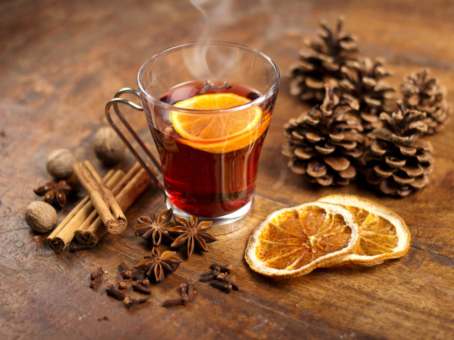 Чай с лимоном в чашке на столе с корицей, бадьяном и шишками