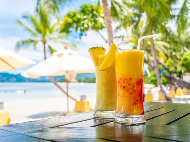 Два цитрусовых коктейля на столе на тропическом пляже
