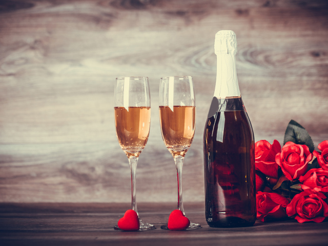 Два бокала и бутылка шампанского на столе с букетом роз