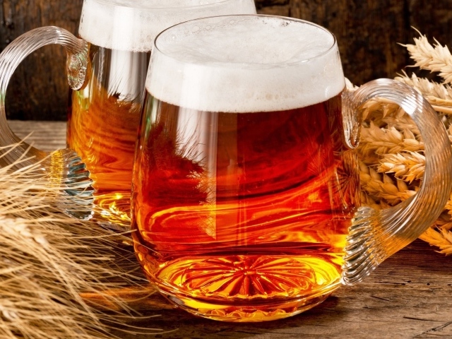 Два бокала пива на столе с колосьями пшеницы