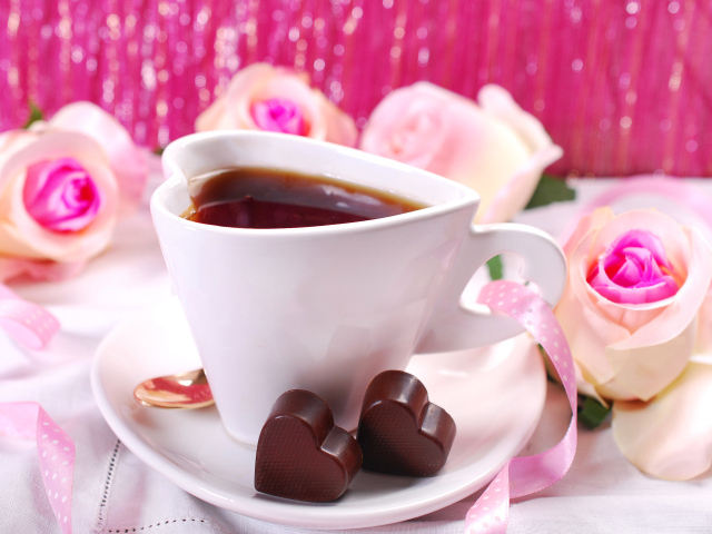 Белая чашка в форме сердца с кофе на блюдце с конфетами