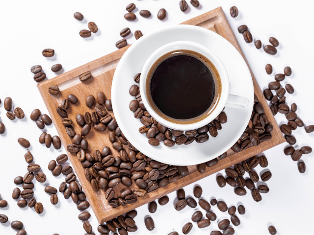 Белая чашка кофе на доске с кофейными зернами