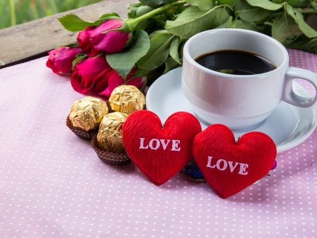 Белая чашка кофе на столе с букетом роз, конфетами и красными сердечками