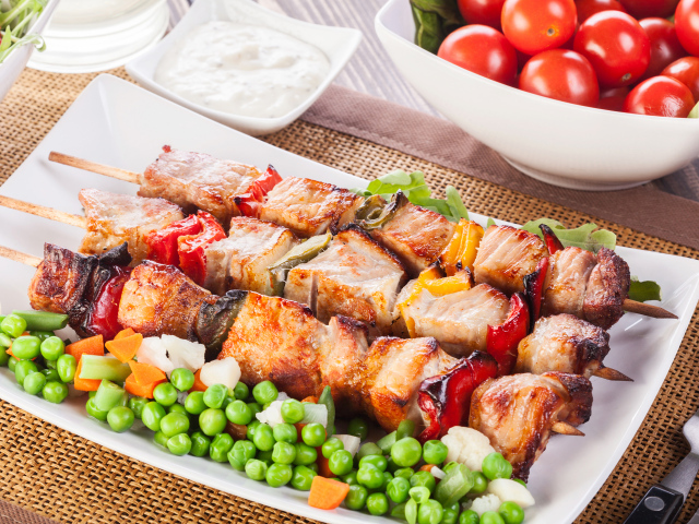 Аппетитный румяный шашлык с зеленым горошком на тарелке