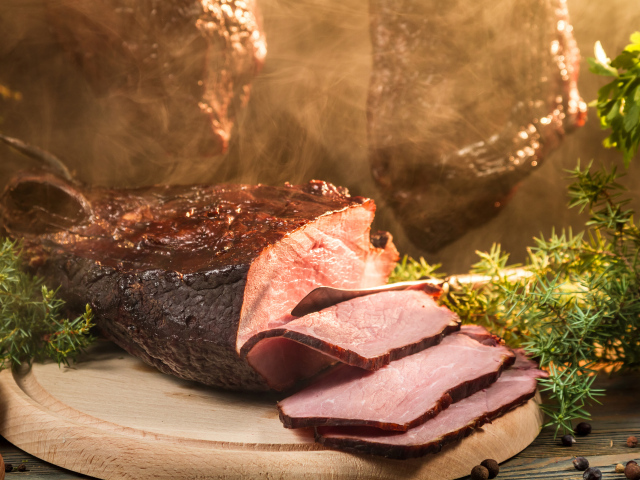 Аппетитный кусок сочной ветчины нарезан на разделочной доске