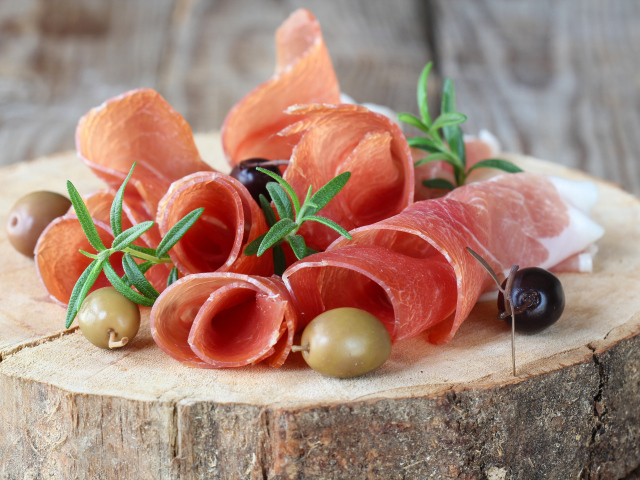 Прошутто  с оливками на деревянном столе 