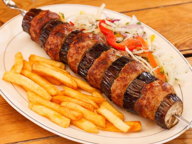 Шашлык с мясом и баклажанами на тарелке с картофелем фри 