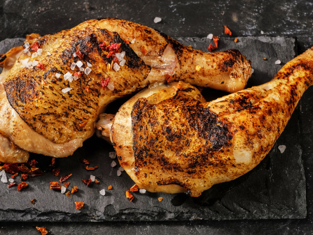 Два запеченных куриных окорочка на черном фоне