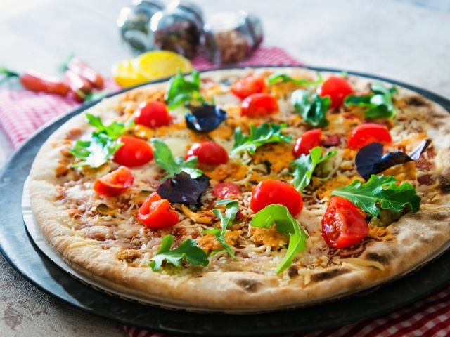 Пицца с помидорами, рукколой и сыром на столе