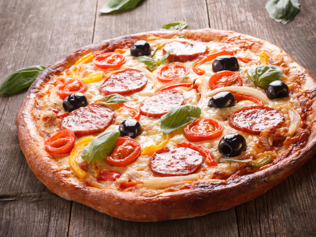 Румяная пицца с колбасой, помидорами, оливками и сыром