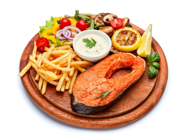 Рыба на доске с картофелем фри, овощами и соусом