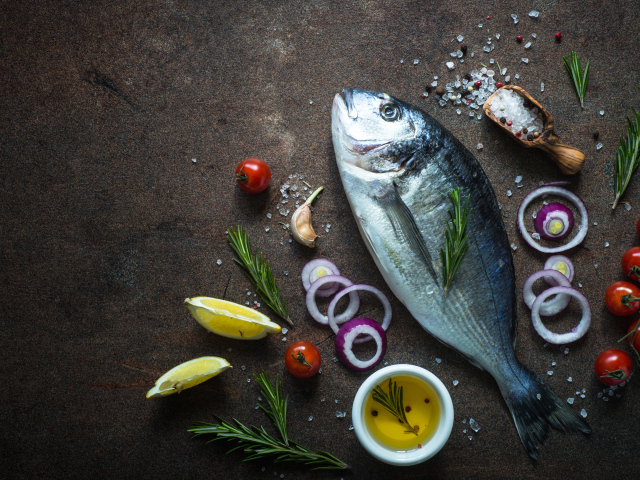 Свежая рыба на столе с овощами и специями 