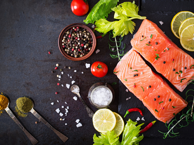 Куски красной рыбы на столе с лимоном и специями