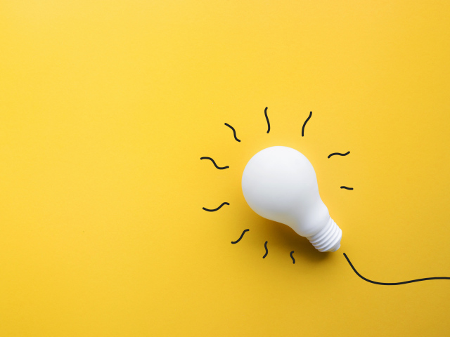 Белая лампочка лежит на желтой поверхности 
