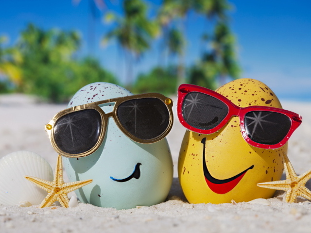 Два яйца в солнечных очках на морском песке летом