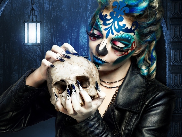 Девушка с гримом на лице с черепом в руках на Хэллоуин 