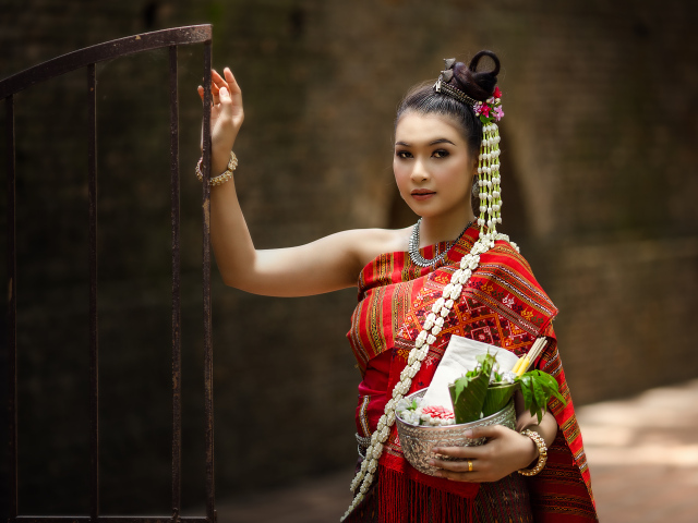 Девушка азиатка в костюме стоит у железных ворот