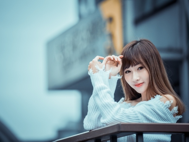 Молодая девушка азиатка в белом свитере на балконе