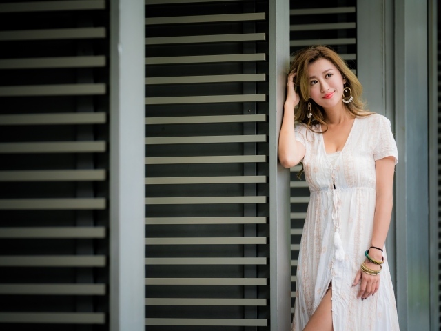 Красивая девушка азиатка в платье стоит у дверей