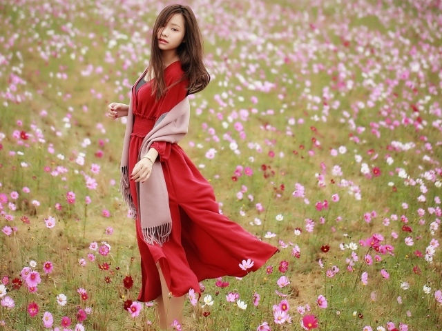 Красивая азиатка в красном платье на поле с цветами космеи