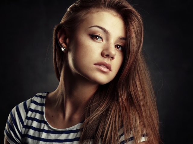 Красивая кареглазая девушка с русыми волосами на сером фоне