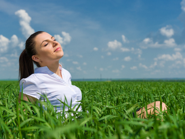 Красивая девушка нежится на солнце в зеленой траве