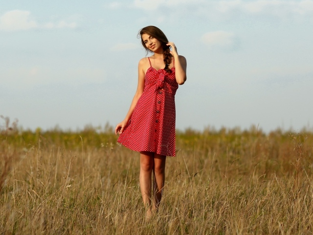 Красивая девушка в красном сарафане на поле 