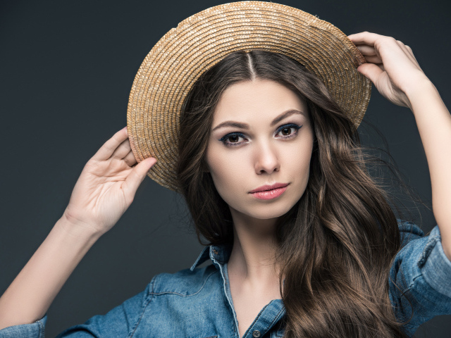 Красивая девушка в соломенной шляпе на сером фоне