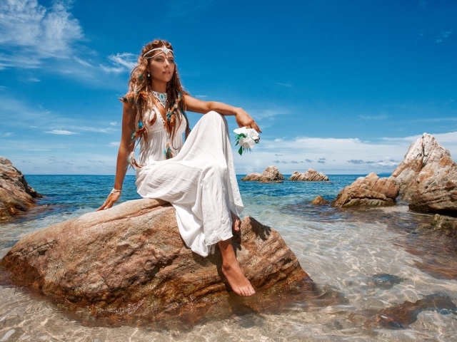 Красивая девушка в белом платье сидит на камне в воде