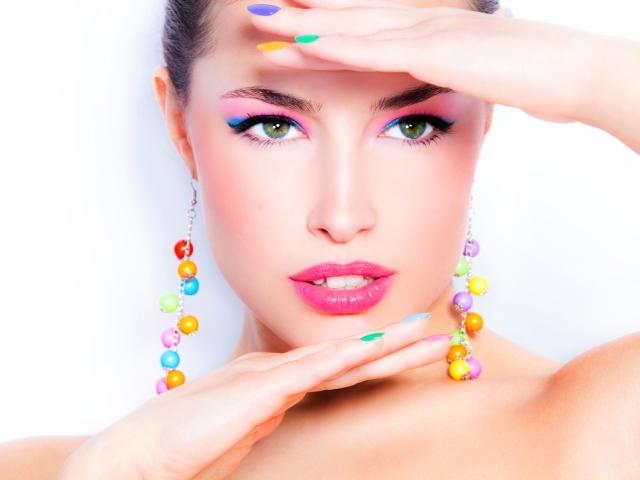 Красивая девушка с ярким макияжем и разноцветным маникюром на ногтях