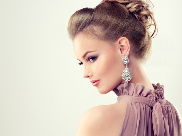 Красивая девушка с макияжем и прической на сером фоне