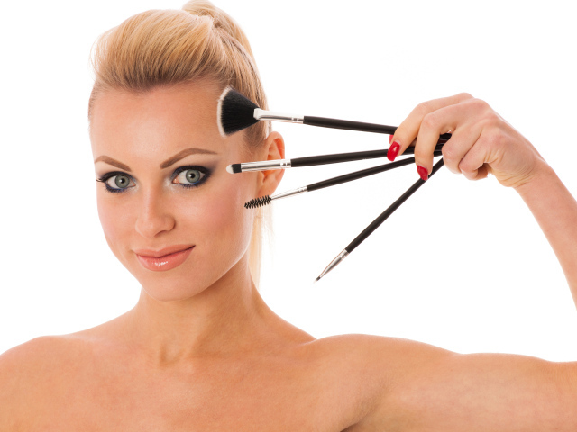 Красивая девушка с кистями для макияжа на белом фоне