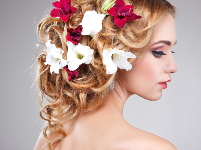 Красивая девушка с цветами петунии в волосах на сером фоне