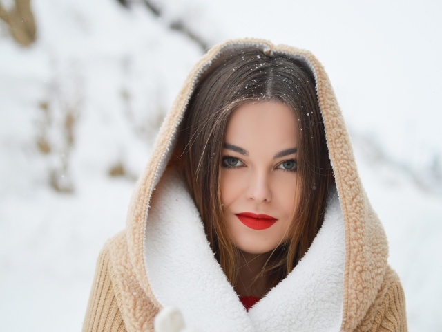 Красивая девушка с красными губами в теплой куртке зимой