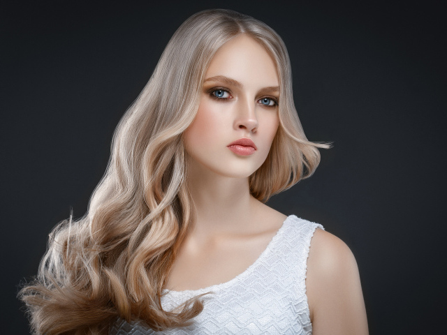 Красивая длинноволосая блондинка с голубыми глазами на сером фоне