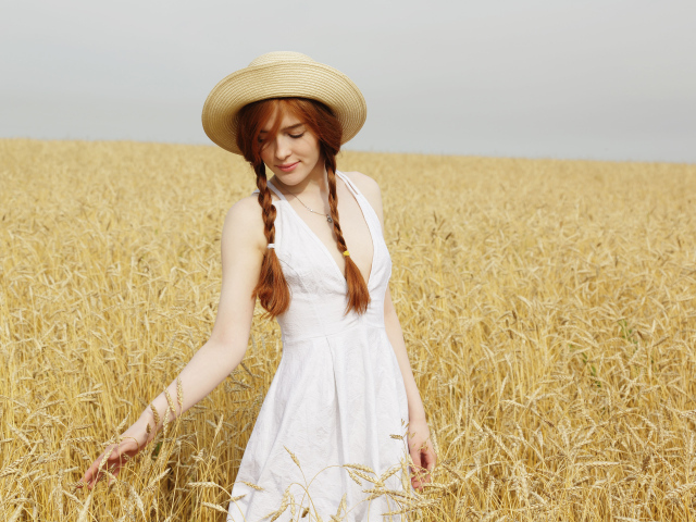 Красивая рыжеволосая девушка гуляет по полю с пшеницей