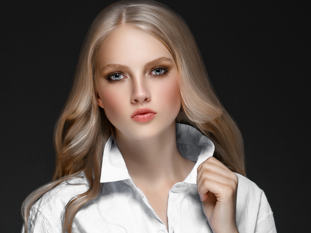 Красивая стильная голубоглазая блондинка в белой рубашке на сером фоне