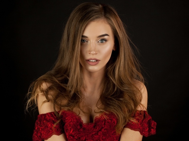 Красивая нежная длинноволосая шатенка в красном платье на черном фоне