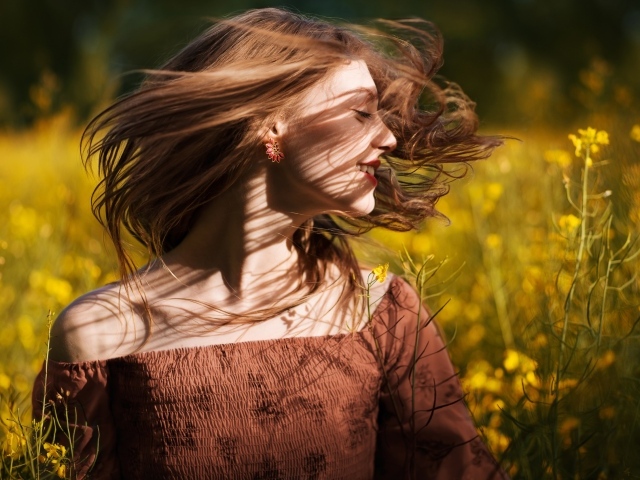 Красивая молодая девушка на поле с желтыми цветами