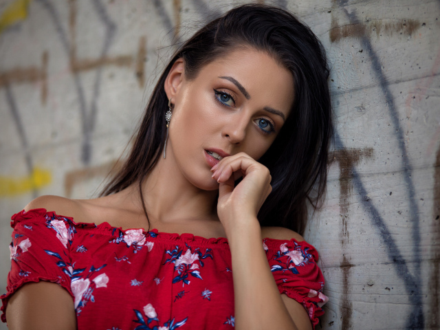 Голубоглазая брюнетка стоит в платье стоит стены